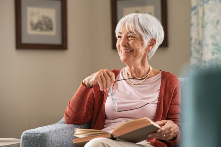 Mujer mayor leyendo un libro con una sonrisa en su rostro