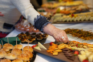 Mano de una persona mayor seleccionando aperitivos en un evento