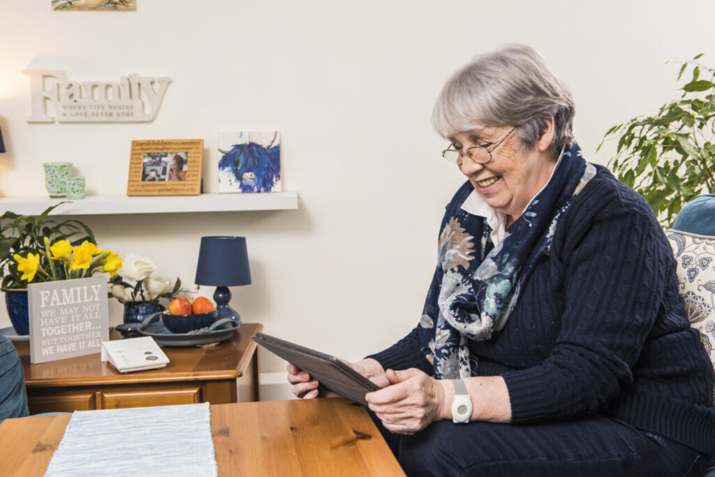 Mujer mayor usando una tablet en un ambiente acogedor