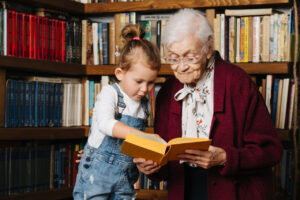 Una ni&ntilde;a y una anciana leyendo juntas en una biblioteca
