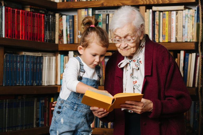 Una ni&ntilde;a y una anciana leyendo juntas en una biblioteca