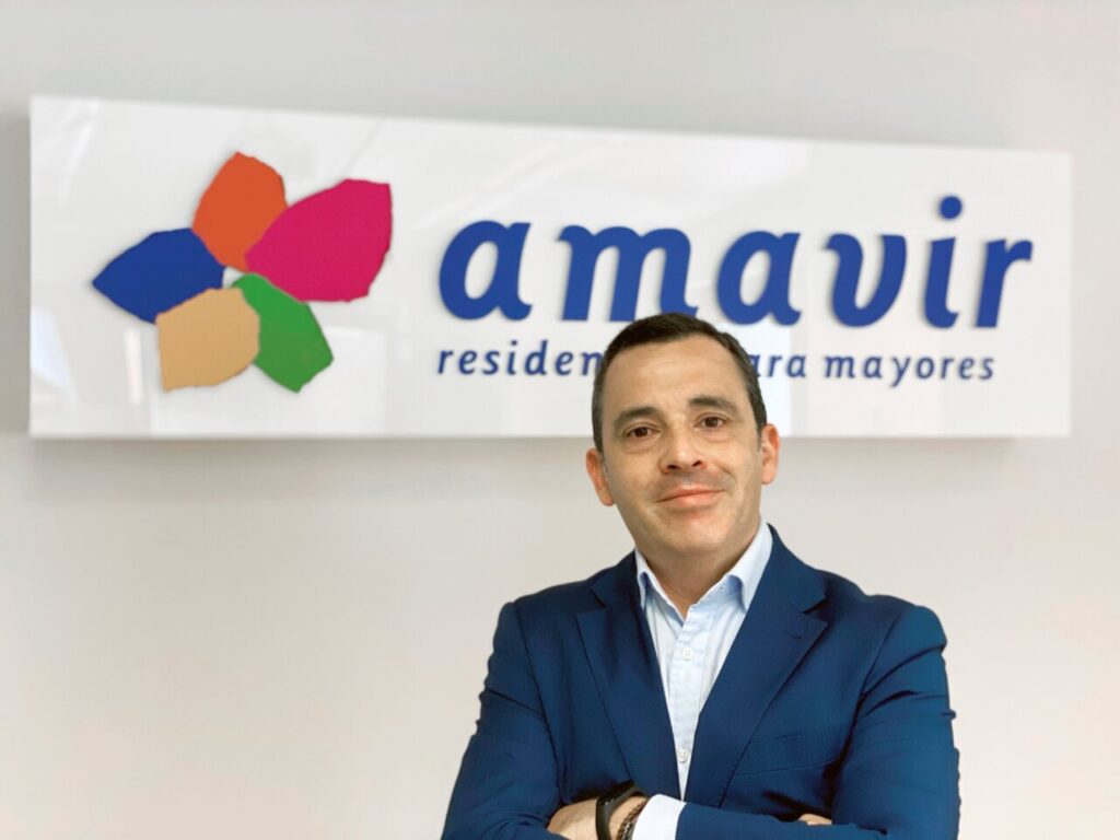 Director de Amavir posando frente a un cartel de la empresa