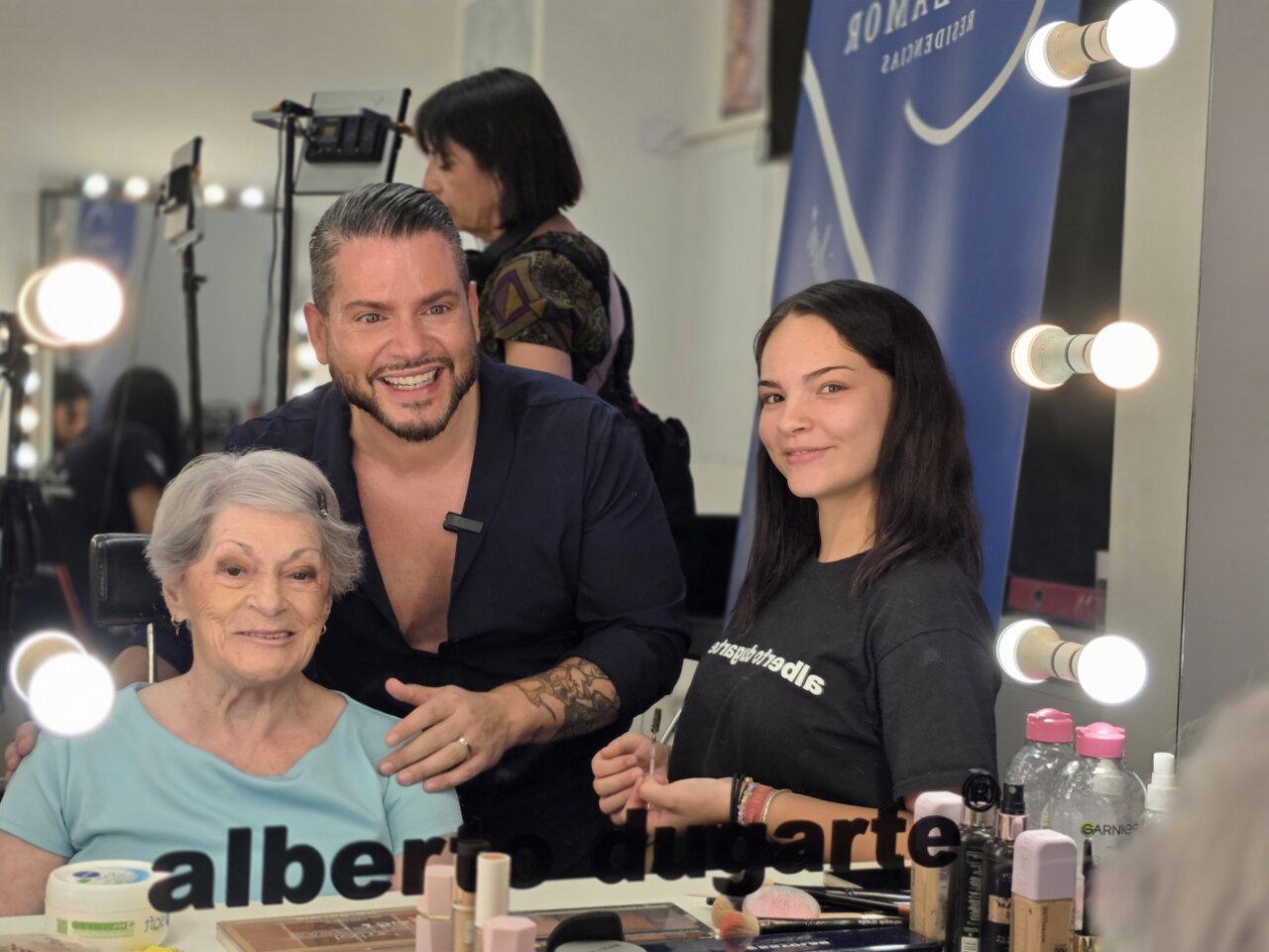 Alberto Dugarte maquillando a una mujer mayor en un ambiente de belleza