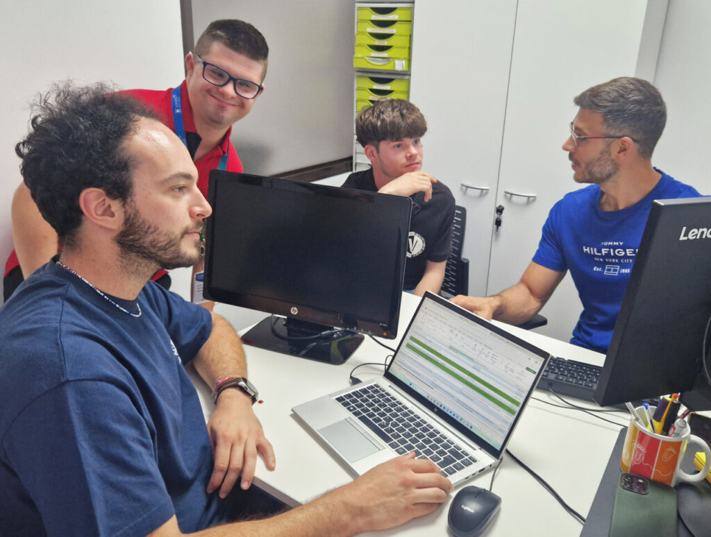 J&oacute;venes en pr&aacute;cticas en un entorno laboral inclusivo con ordenadores.