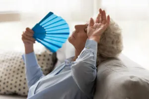 Mujer mayor usando un abanico para refrescarse en verano