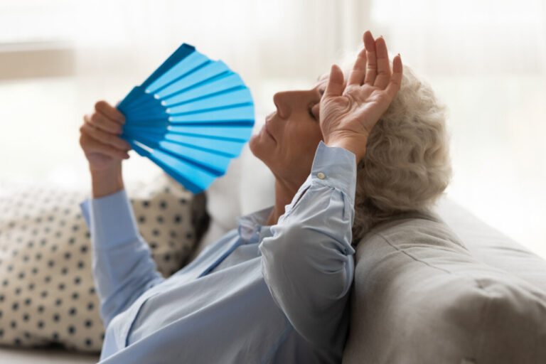 Mujer mayor usando un abanico para refrescarse en verano