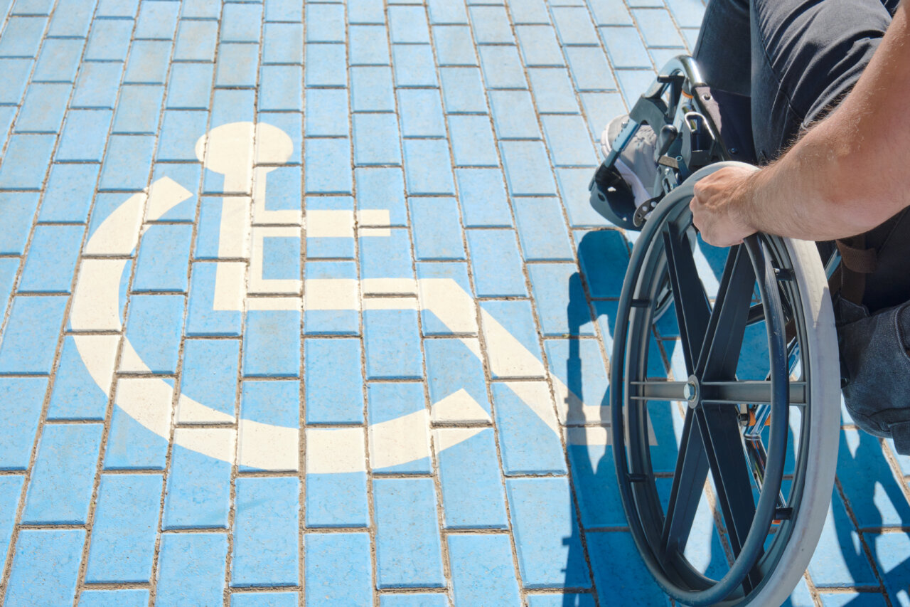 Persona en silla de ruedas sobre un pavimento marcado con símbolo de discapacidad
