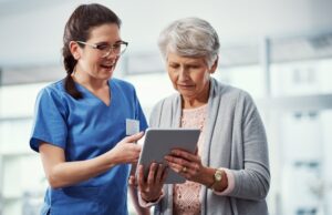 Profesional de la salud ayuda a una persona mayor con una tablet