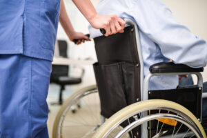 Profesional de la salud empujando una silla de ruedas en un entorno clínico