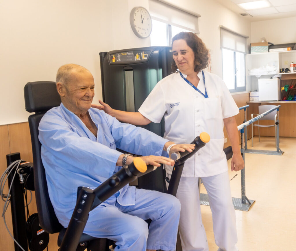Paciente mayor realizando una prueba física en el hospital con la ayuda de un profesional de la salud.