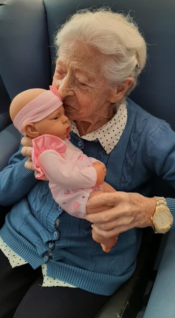 Anciana abrazando una muñeca Reborn en un entorno de terapia