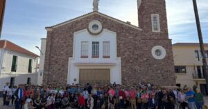 Grupo numeroso posa frente a una iglesia de piedra en Cabezarrubias del Puerto