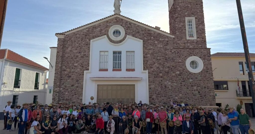 Grupo numeroso posa frente a una iglesia de piedra en Cabezarrubias del Puerto