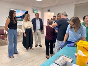 Personal sanitario atiende a una persona mayor junto a una bandeja con jeringas.